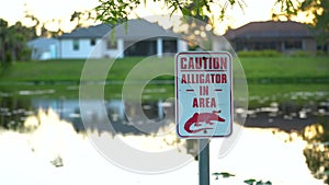 Warning sign about alligator in water in Florida park. Caution and safety during walking near waterfront