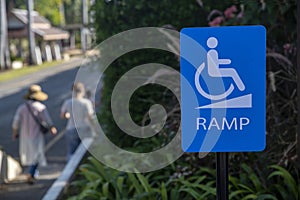 Warning sign be careful of ramp floor for disabled, white handicapped symbol sitting on wheelchair going up ramp on blue metal