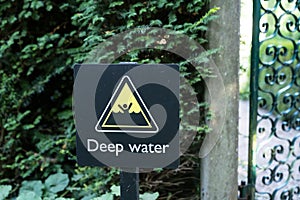 A warning sign in black and yellow indicating the danger of drowning in deep water forbidding people to swim, english language