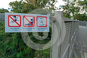 A warning sign at the canopy walkway in a botanical garden.