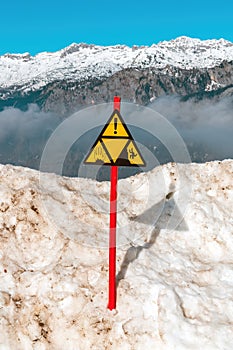 Warning sign at cliff on snow capped mountain in Triglav national park in Slovenia