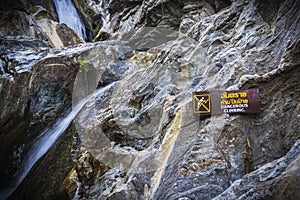Warning Sign dangerous climbing at waterfall with stones.
