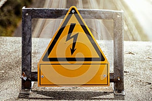 warning sign electricity on a bridge at a railroad track in sunshine