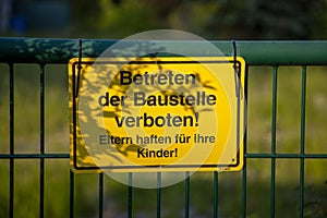 A warning sign on a fence with German text translates into construction site do not enter in English language