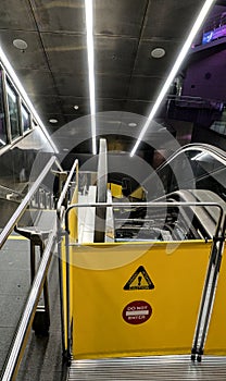 Warning sign in front of broken escalator under repair inside world trade center train station.