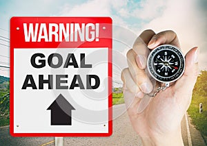 Warning sign goal ahead with hand holding compass