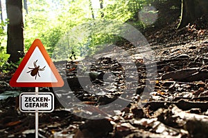 Warning sign for infected ticks in a forest. Risk of tick and Lyme disease.