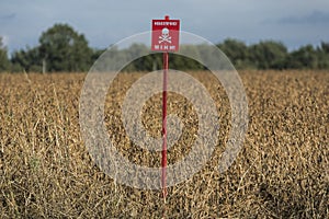 A warning sign with the inscription in Ukrainian DANGEROUS - MINE is installed in a farmer's field in northern