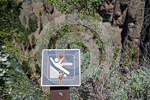 Warning sign of loose rocks and falling and slipping danger along a hiking trail