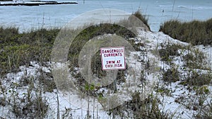 Warning sign next to a lake reading dangerous currents in winter