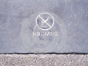 Warning sign No Diving on concrete floor beside swimming pool