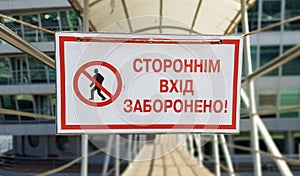 Warning sign No unauthorized entry written in red text in Ukrainian on a white rectangular table. The sign prohibits the passage photo