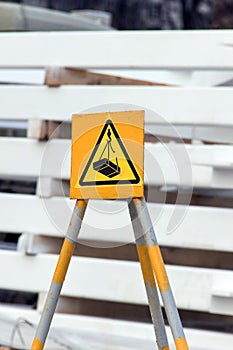warning sign of a possible drop in cargo from a crane on a yellow background