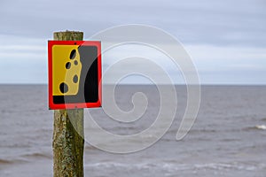 A warning sign about a possible landslide near the seashore. Reflects the idea of the concept of caution and warning