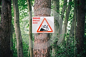 Warning sign on russian language: Warning, steep slope. Cyclist Caution, steep slope and slow down warning sign on a