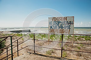 Warning sign on the shore. Text in Russian: the beach is not equipped. swimming is forbidden