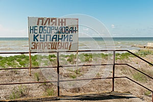 Warning sign on the shore. Text in Russian: the beach is not equipped. swimming is forbidden