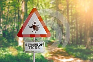 Warning sign with text BEWARE OF TICKS, against defocused forest background