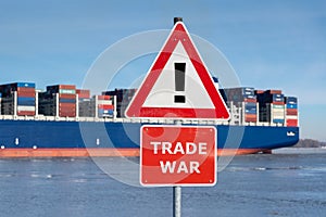 Warning sign with the text `Trade war` in front of a huge container ship.