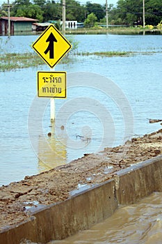 A warning sign to be careful on the flooded path.