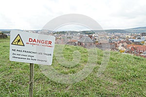 Warning sign to prevent tip over, overturn, in English, German and French language attached to wooden stick .