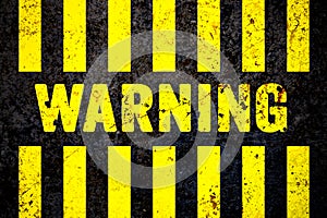 Warning sign with yellow and black stripes painted over cracked concrete wall coarse texture background