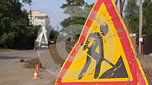 Warning signs on closed road under construction with arrow sign, hinders traffic in the city. On the background tractor