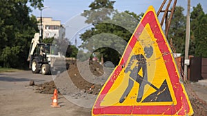 Warning signs on closed road under construction with arrow sign, hinders traffic in the city. On the background tractor