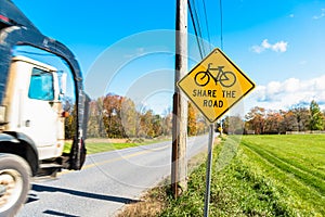 Warning traffic sign telling drivers to share the road with cyclists on a clear autumn day