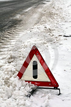 Warning triangle at snowy road.