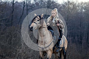 Warrior viking blonde female riding a horse in the woods - Medieval movie scene - Focus on the rider