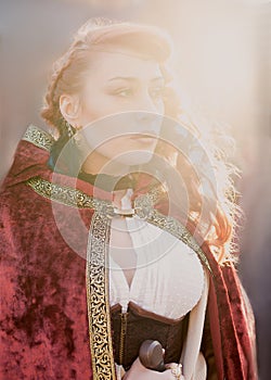 Warrior woman with sword in medieval clothes in sun light