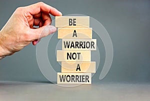 Warrior or worrier symbol. Concept words Be a warrior not a worrier on wooden blocks on a beautiful grey table grey background.