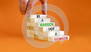 Warrior or worrier symbol. Concept words Be a warrior not a worrier on wooden blocks on a beautiful orange table orange background