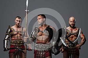 Warriors gladiators with swords and spear against gray background