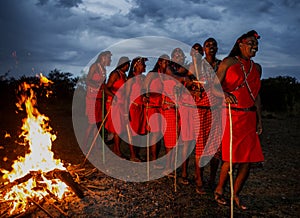 Warriors the Masai tribe dancing ritual dance around the fire late in the evening.