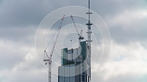 Warsaw, Poland - 07.09.2021: Skyscraper construction site time-lapse. Varso tower, tower cranes working with clouds