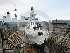 Warship M33 in drydock with HMS dauntless in the background