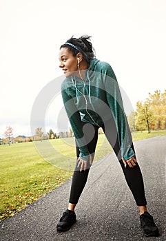 That was a good run. Whats next. an attractive young woman taking a break while out for a run in nature.