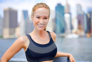 That was a good workout. Portrait of a beautiful young woman standing beside a river while out for a run in the city.