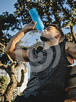 That was quite a workout. Low angle shot of a sporty young man drinking water while exercising outdoors.