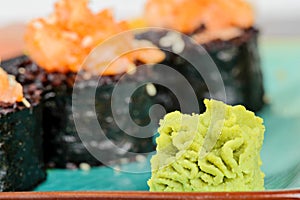 Wasabi with baked sushi rolls on turquoise plate