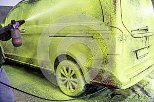 wash car with green active foam on a hand washer