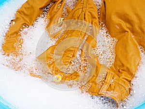 Wash colored clothes with yellow pants, soaked washing with laundry detergent solution in tub.