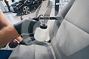 Wash dirt seat textile in car service with high-pressure cleaning gun