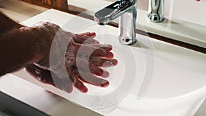 Wash hands between fingers white washbasin water flows from the tap