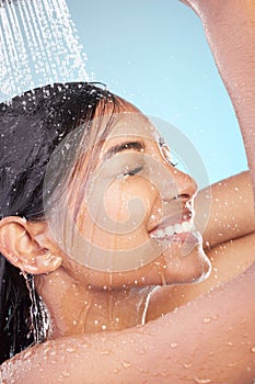 Wash over me. Shot of a young woman washing her hair in the shower against a blue background.