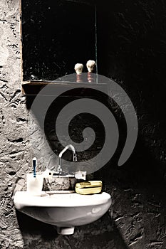 Washbasin with a mug for a toothbrush and a soap box on it under