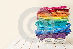 The washed laundry is in the basket. Bright rainbow clothing is