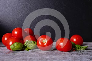 Washed ripe tomatoes and basil leaves, on black background